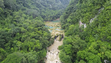 drone aerial footage of guatemalan rainforest semuc champey national park and river rio cahabon surrounded by bright green rainforest hillsides and mountains