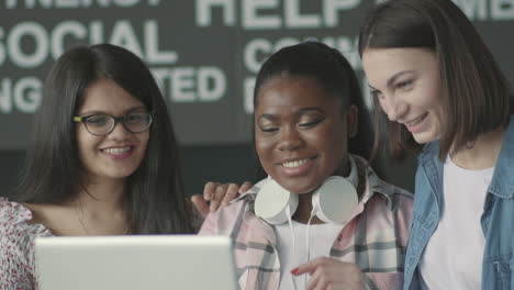 grupo multicultural de estudiantes riéndose frente a una laptop