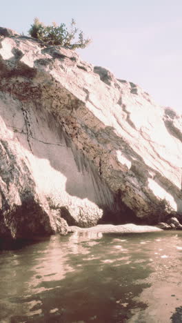 a large rock cliff overlooking a calm sea