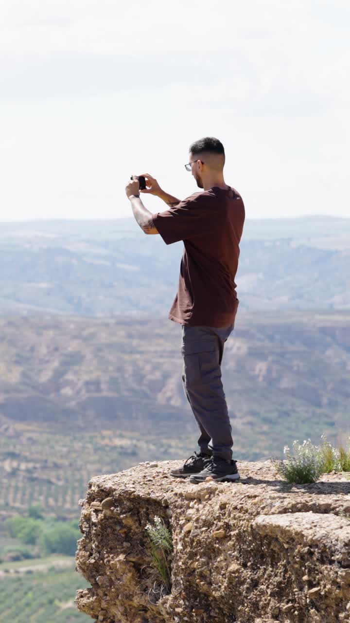 Man and dog sitting on cliff edge in gorafe, spain. Vertical