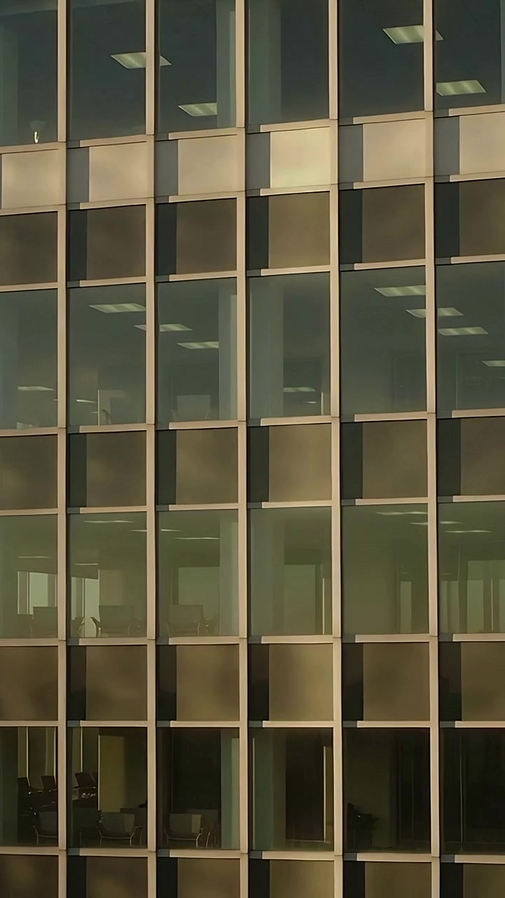 Vertical video: Starting camera right sweep, panning office showing desks via glass to catch light