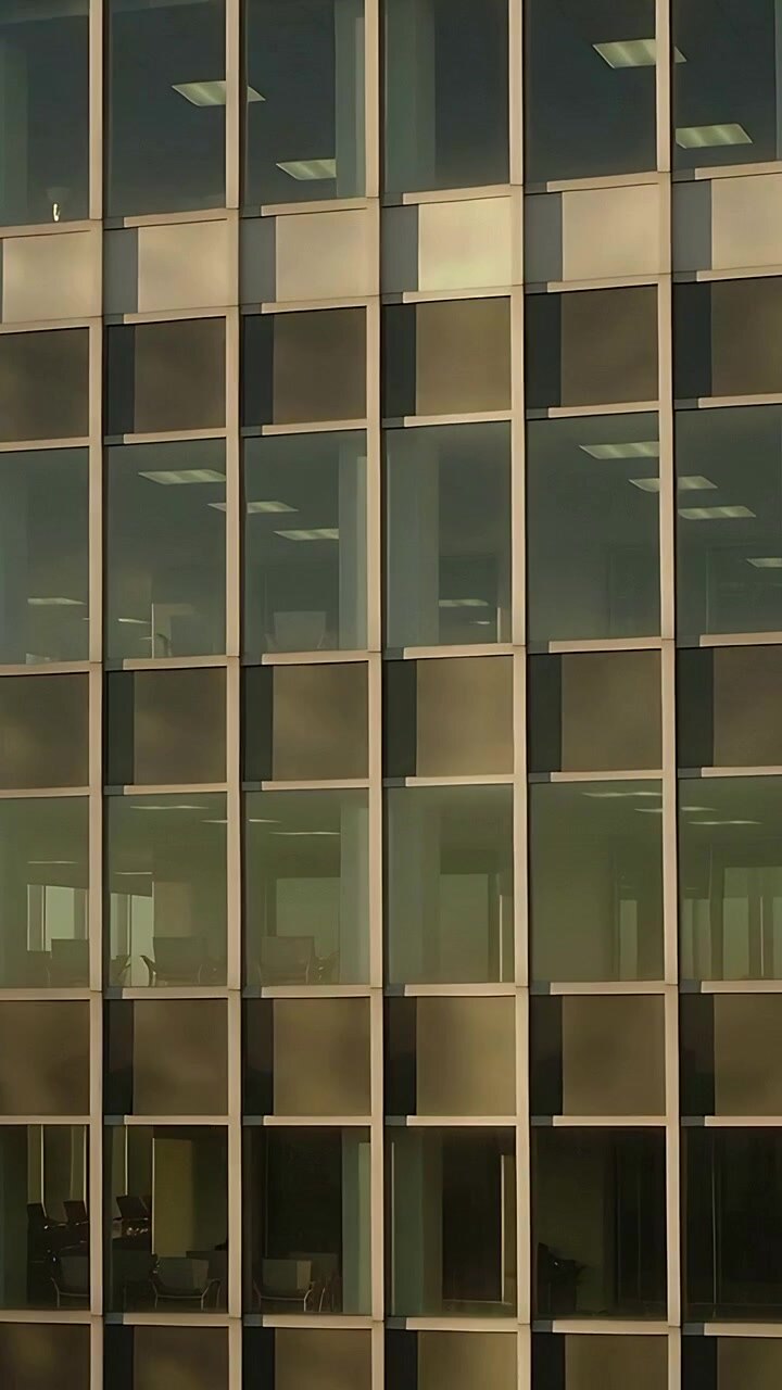 Video verticale: avvio della telecamera con panoramica verso destra, inquadratura dell'ufficio che mostra le scrivanie attraverso il vetro per catturare la luce