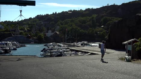 Young-guy-is-longboarding-at-the-docks-on-the-beach-in-Norway-at-Kjerringvik