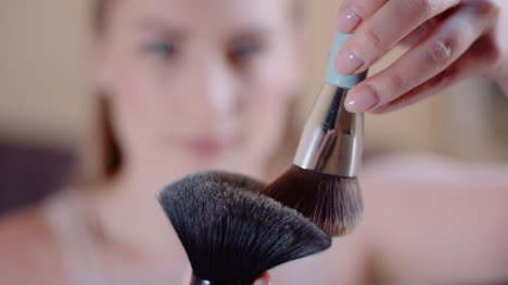 young woman using brush and powder while doing make up