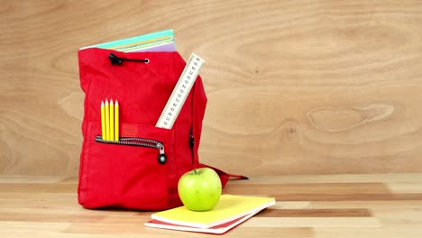 primer plano de la bolsa escolar con libros, manzana y papelería
