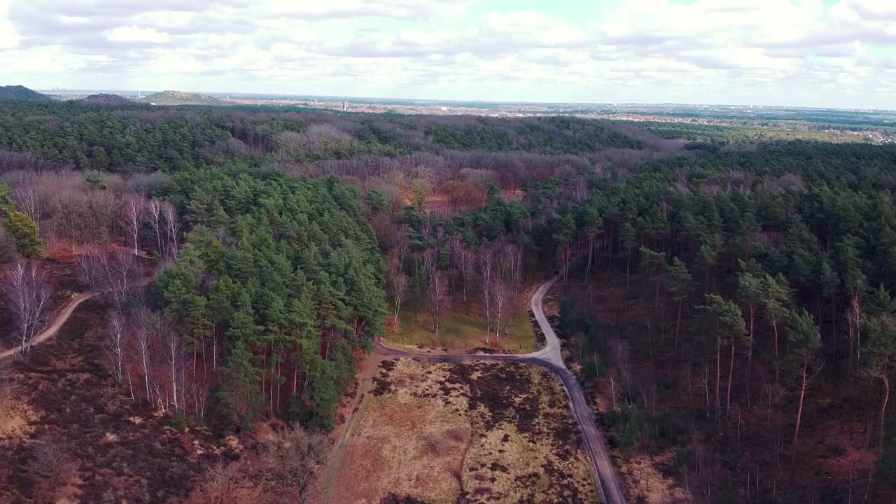 Luftfoto af naturskønt belgisk skovlandskab med vandrestier, en fjern by og landbrugsmarker i de Mechelse heide.