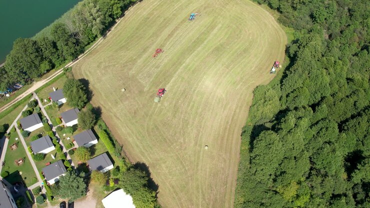 Agriculture Machinery Working in Green Field, Tractors and Hay Bales Machines Harvesting in Agricultural Farmland, Aerial Top Down View of Farm Agricultural Work