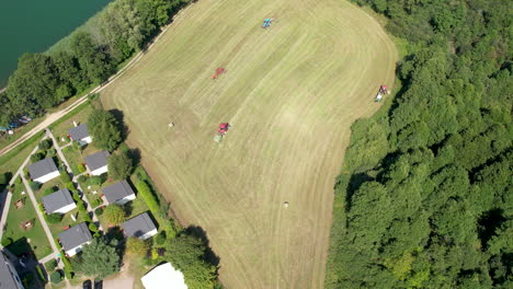 agriculture machinery working in green field, tractors and hay bales machines harvesting in agricultural farmland, aerial top down view of farm agricultural work