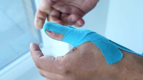 man taking kinesiology tape off his thumb