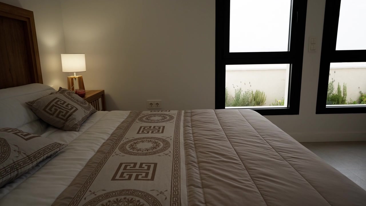 Interno di una camera da letto moderna con letto king size, illuminazione ambientale soffusa e arredamento minimalista all'interno di un appartamento di lusso contemporaneo o di una proprietà per vacanze