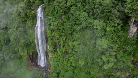 aerial truck left of las lajas waterfall flowing down high cliff surrounded by rain forest, san luis morete, costa rica