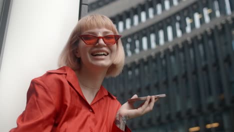 young woman laughing on smartphone in city