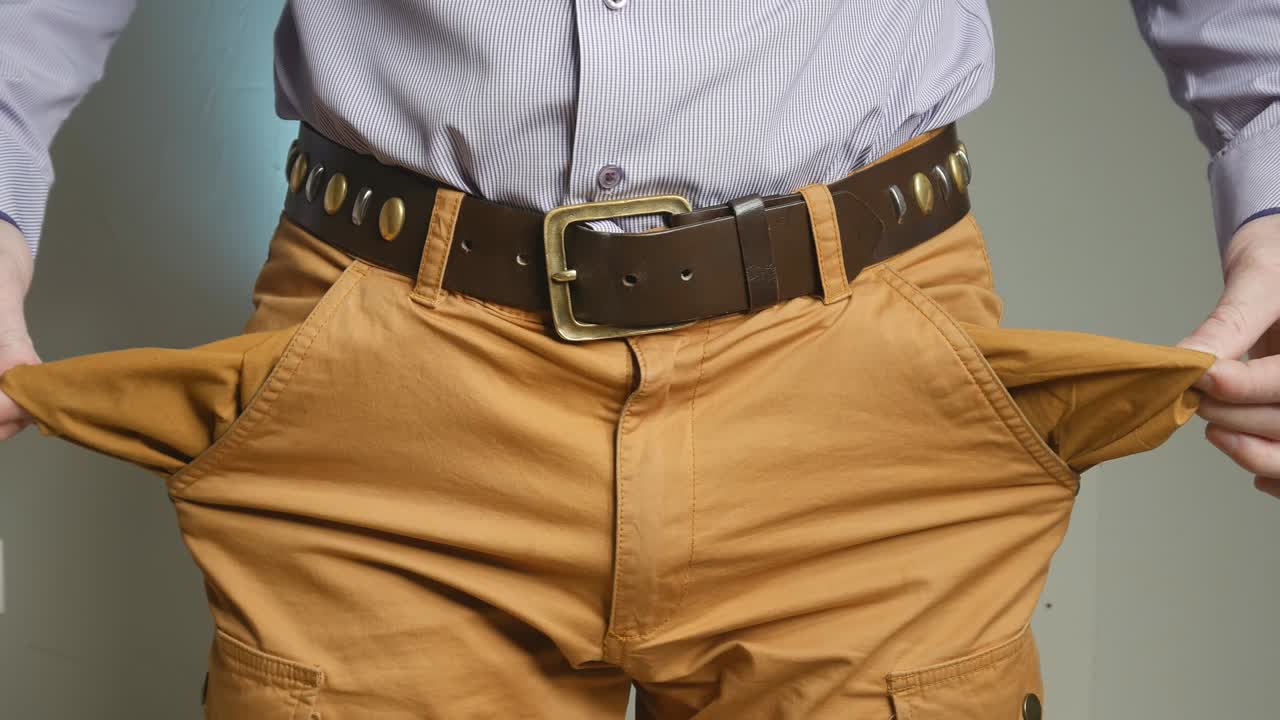 el hombre de negocios muestra los bolsillos vacíos de sus pantalones. se abrió los bolsillo con las manos para que estuvieran vacíos.
