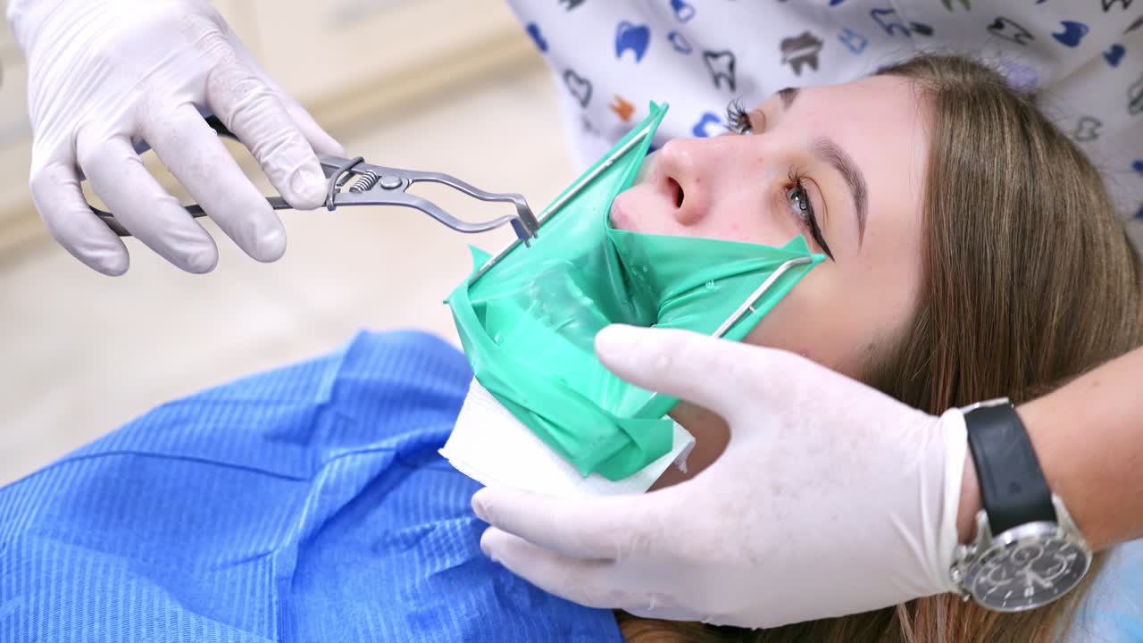 Patient in dental chair. Beautiful young woman having dental treatment at dentist office