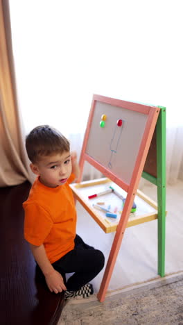 little kid plays with colorful magnets on the whiteboard. toddler boy learning colors. top view. vertical video.