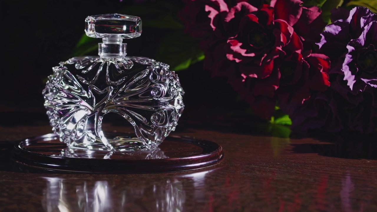 Elegante boccetta di profumo in cristallo su un tavolo di legno con fiori.