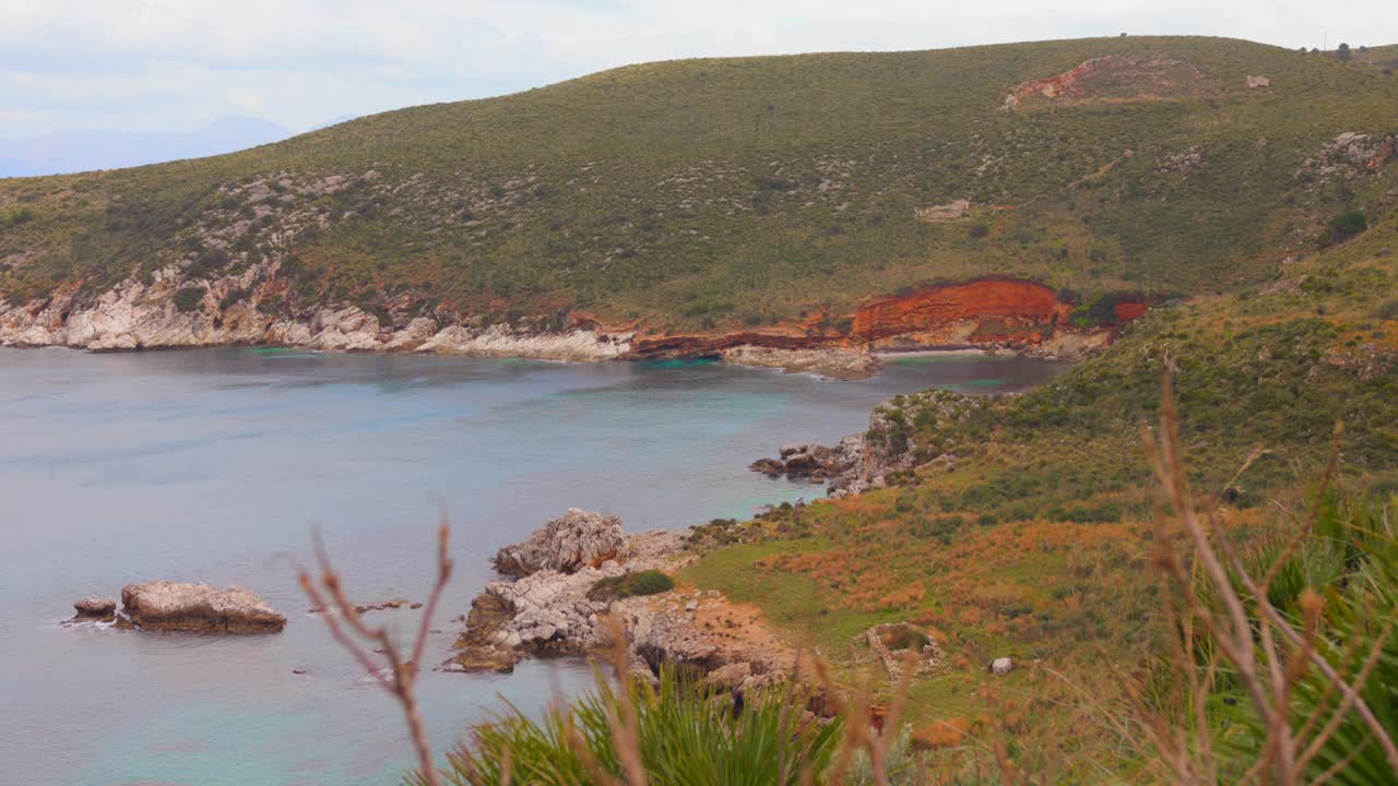 Shot of Cala Bianca from a distance in Sicily, Italy. "White cove". Green vegetation on hills.