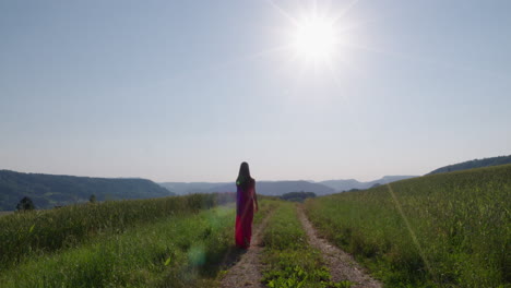 una mujer con un vestido rojo camina por un paisaje natural