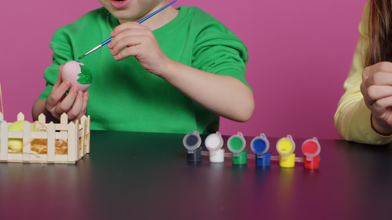 niños pequeños felices usando acuarela y sellos para pintar huevos
