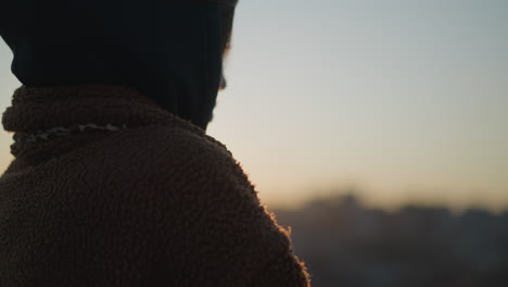 close-up of a sorrowful girl wearing a hoodie, standing against the backdrop of a glowing sunset.the warm, golden light highlights her contemplative expression,moment of deep reflection and melancholy