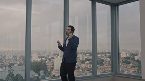 executive man walking and talking on the phone on the terrace of a modern building. camera follows the man.