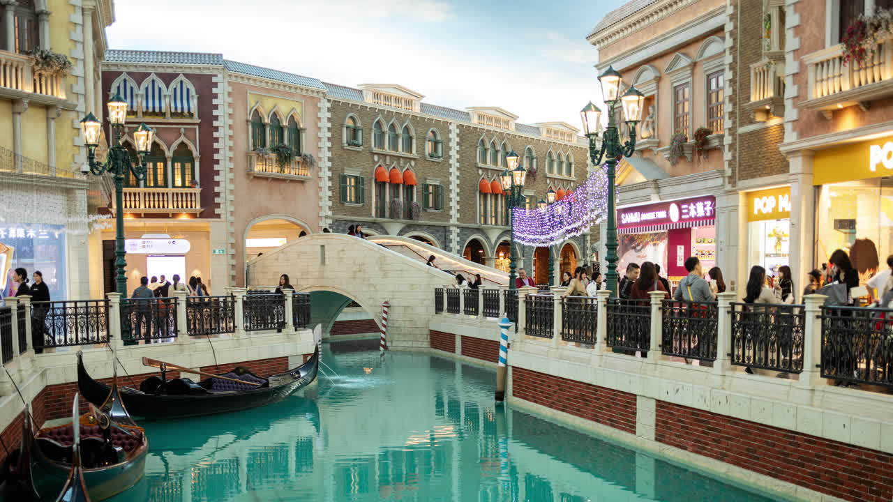 Canale veneziano al coperto con gondole e persone che fanno shopping in un resort di Macao.