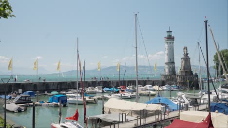 Sonniger-Tag-Im-Hafen-Von-Lindau-Mit-Booten,-Leuchtturm-Und-Statuen,-Klarer-Blauer-Himmel