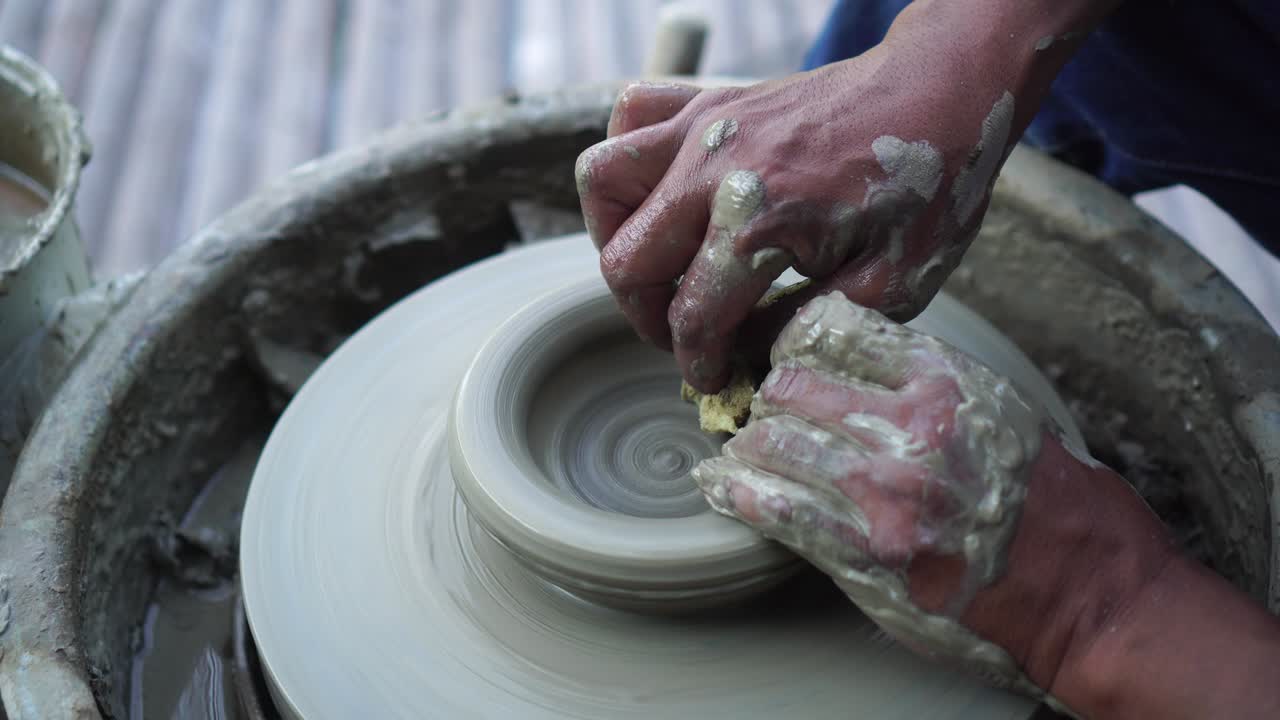 도자기의 바에서 점토를 작업하는 손의 근접. 도자기는 도자기의 에서 도자기 도구로 점토 제품을 형성합니다.