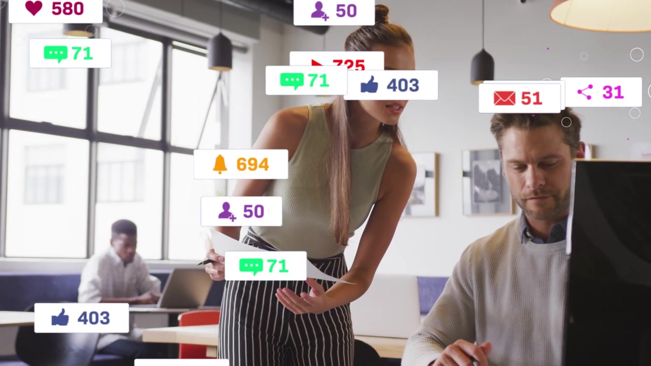 Žena se naklání nad kolegou, ukazuje marketingová data k revizi a zvyšuje počet sledujících na sociálních sítích na monitoru