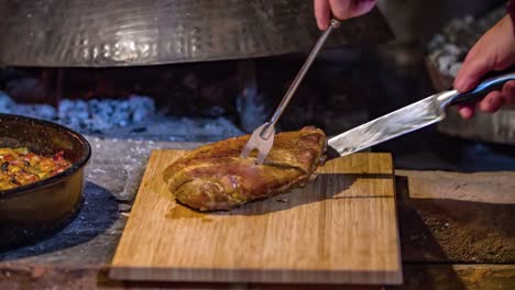 el chef quita el bistec de la sartén, se prepara para cortar en una tabla de cortar de madera