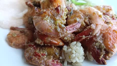 close up of a plate of browned giant prawns and rice on a table