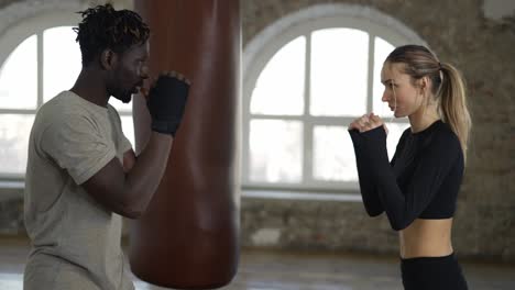 En-Un-Loft-Espacioso,-El-Entrenador-Y-Su-Alumna-Realizan-Una-Sesión-De-Entrenamiento-De-Boxeo