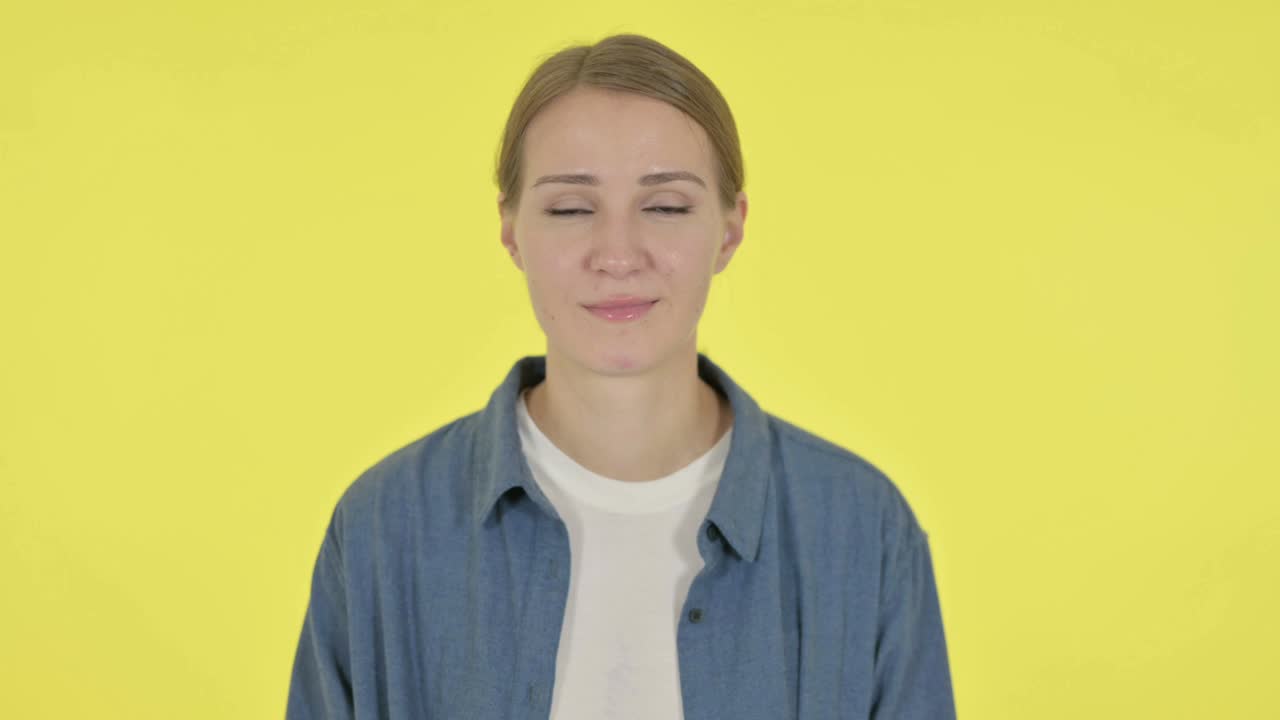 una mujer joven se siente conmocionada sobre un fondo amarillo.