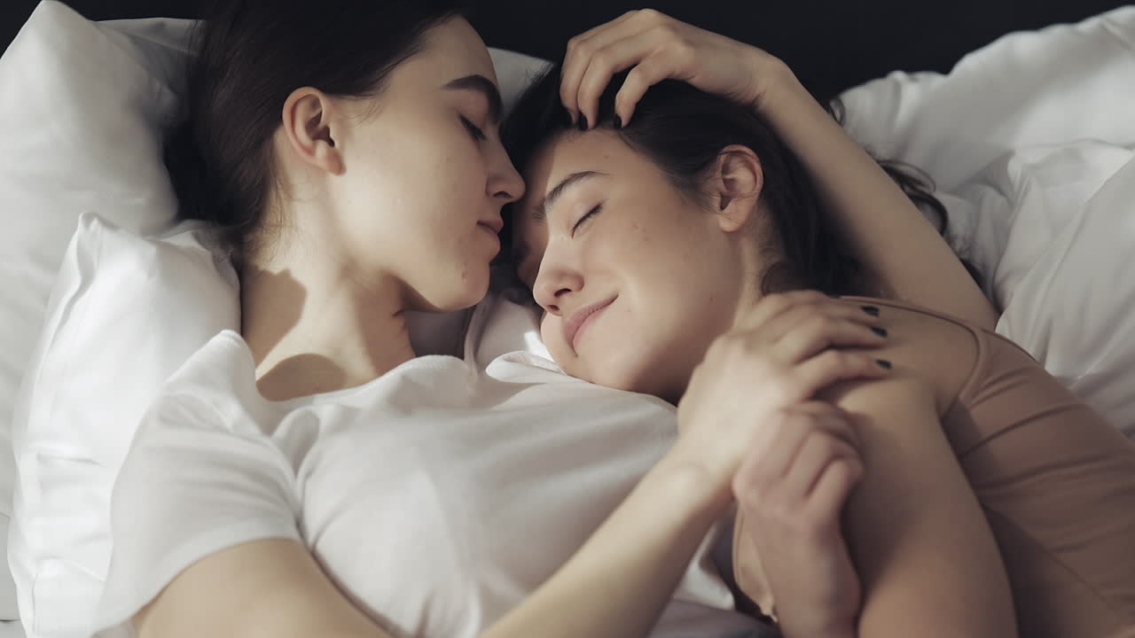 Lesbian couple cuddling in bed