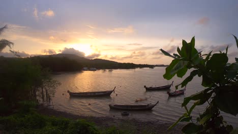 fishing long tail boats anchored in the bay on sea in thailand with a golden sunset in slowmotion