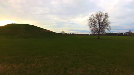 walking in a grass field, with a view of a sunset and a large hill