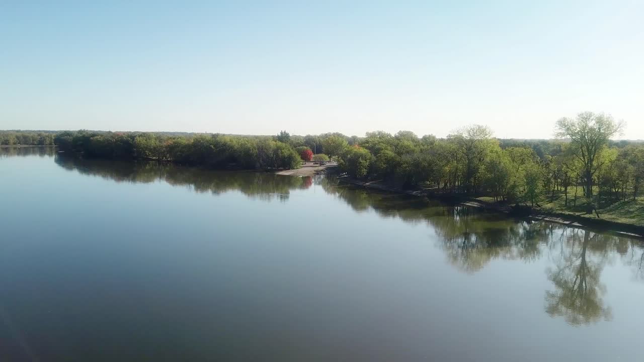 ángulo bajo, vista lenta por drones del río de roca moviéndose hacia una rampa para botes en un soleado día de verano tardío