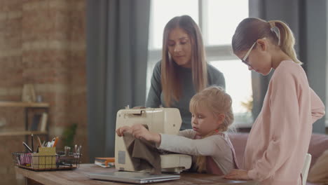 mother and daughters learning to sew