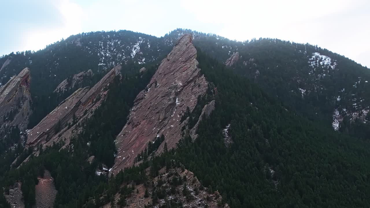 A low drone pass over Boulder Flatirons shadowed cliffs and sunlight in lush landscapes