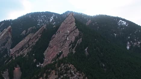 a low drone pass over boulder flatirons shadowed cliffs and sunlight in lush landscapes