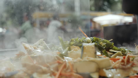 throwing spring onion into steaming wok dish