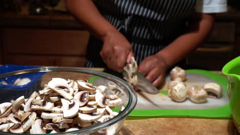 Cook-chops-button-mushroom-to-slices-and-throws-them-into-glass-bowl