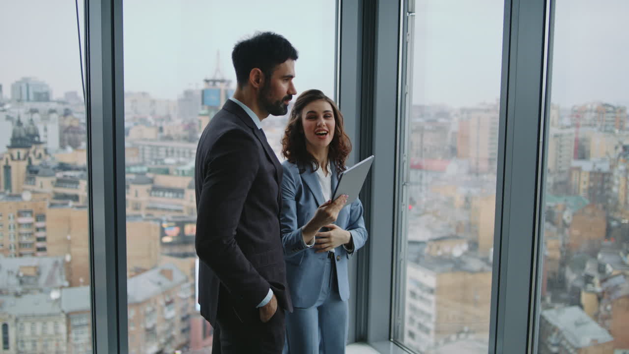 una pareja de compañeros de trabajo hablando de pie en la ventana de la oficina. colegas discutiendo el trabajo.
