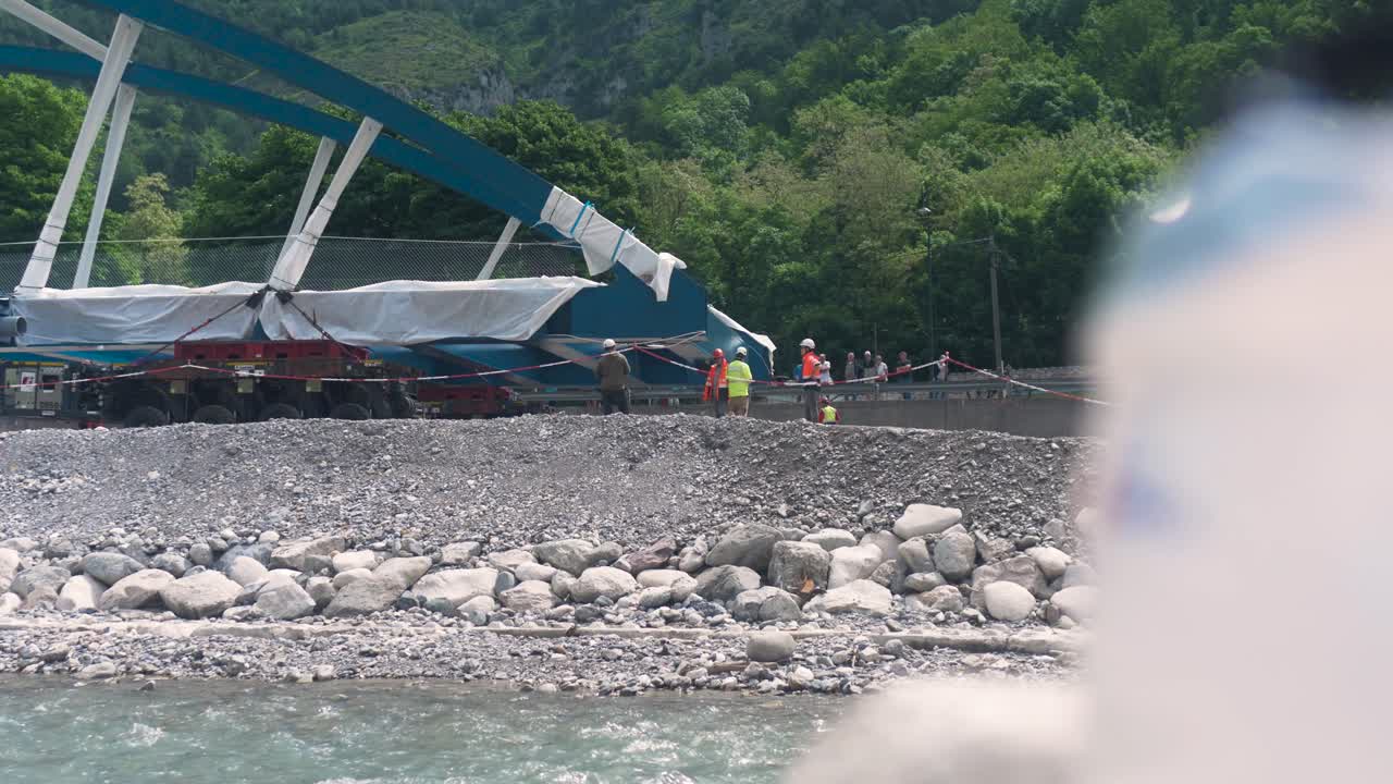 Workers setting up rigging for bridge construction on rocky riverbank in scenic Tende, South of France