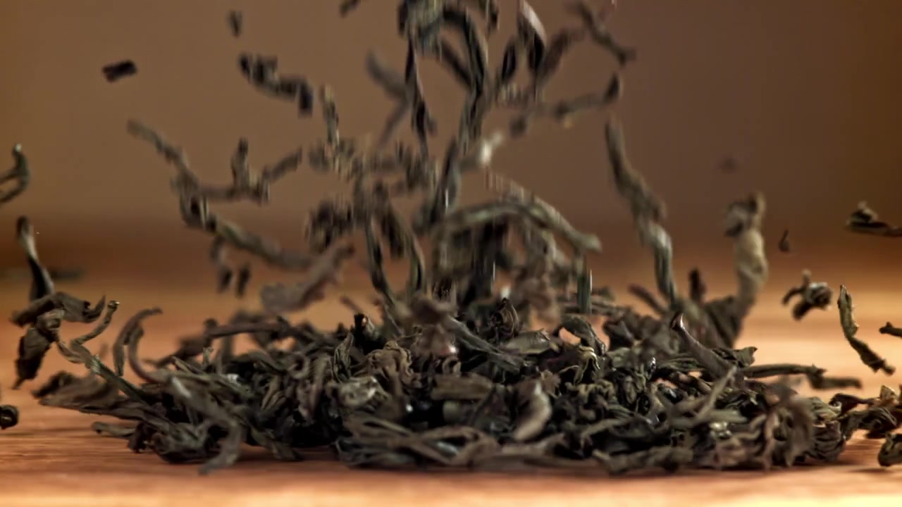 Dried Tea Leaves Falling onto a Wooden Surface in Slow Motion