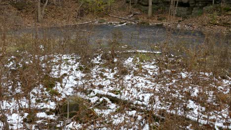 Dramatic-rocky-walls-of-a-natural-quarry-with-frozen-water-in-early-winter