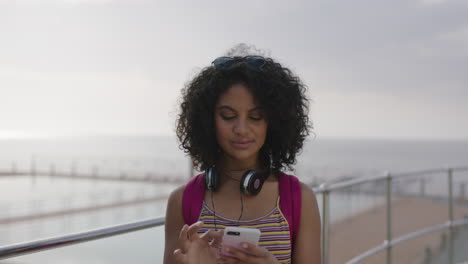 portrait of hispanic woman removes sunglasses smiling texting using smartphone