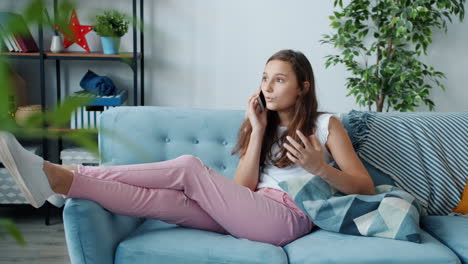 teenage girl relaxing on couch and talking on phone