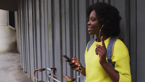 mujer afroamericana usando un teléfono inteligente en la calle