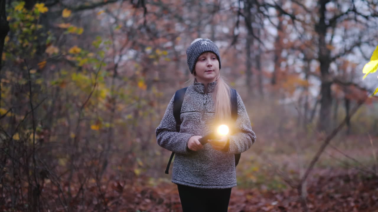 una niña camina por un bosque oscuro con una linterna en la mano se pierde en el concepto del bosque